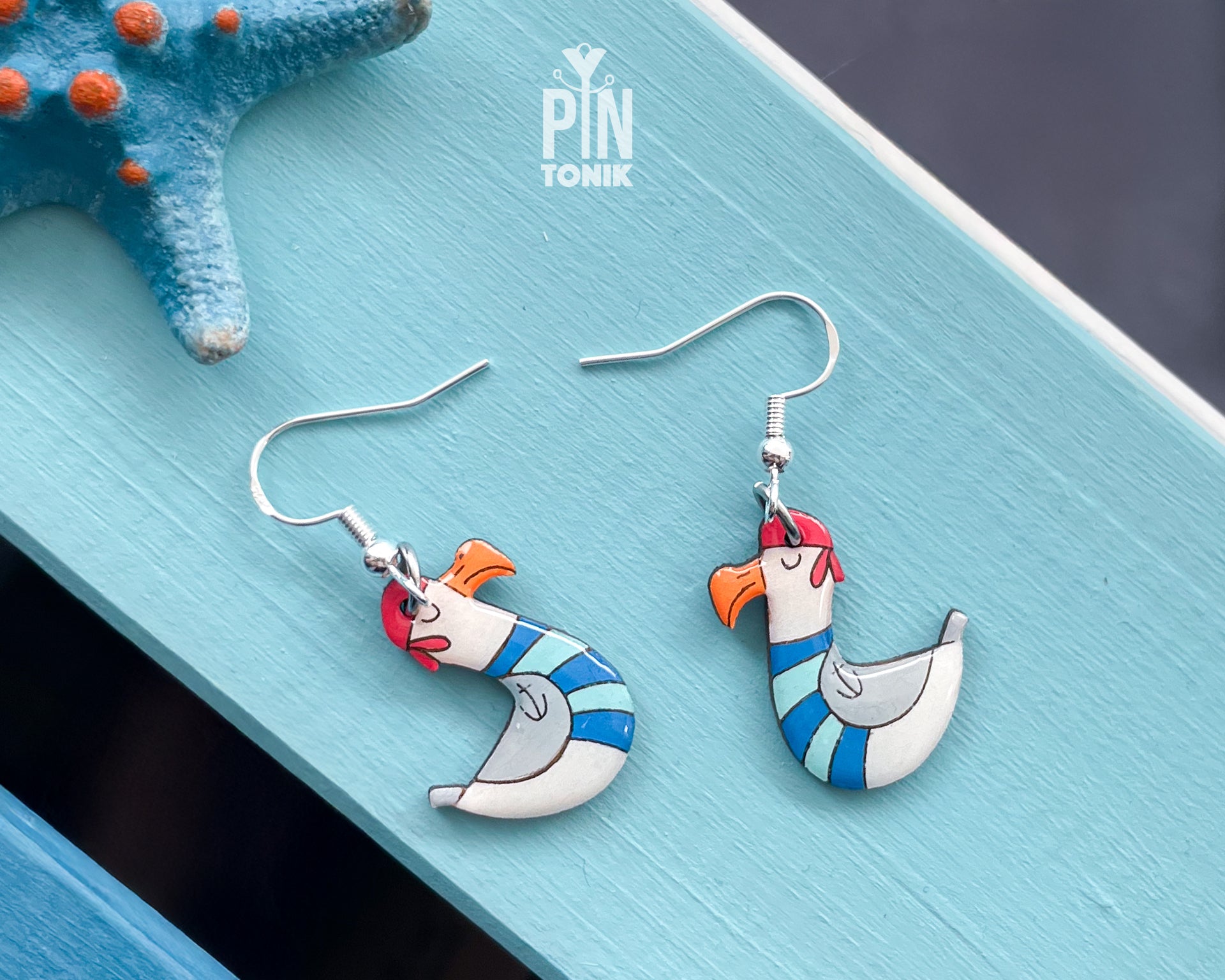 Hand-painted wooden seagull dangle earrings wearing a blue and white striped sailor sweater and a tiny hat on sterling silver hooks