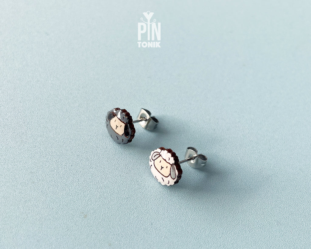 Handmade mismatched wooden sheep stud earrings featuring one black sheep and one white sheep by PinTonik.