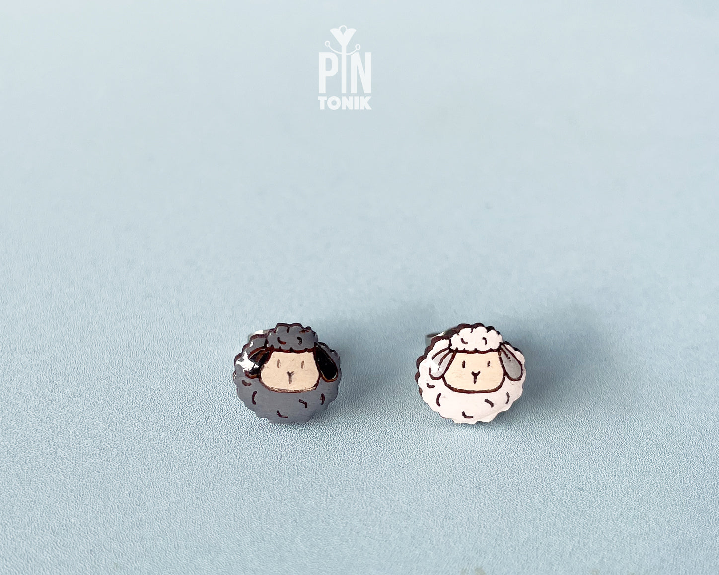 Handmade mismatched wooden sheep stud earrings featuring one black sheep and one white sheep by PinTonik.