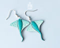Pair of hand-painted teal wooden stingray dangle earrings with white spots and sterling silver hooks
