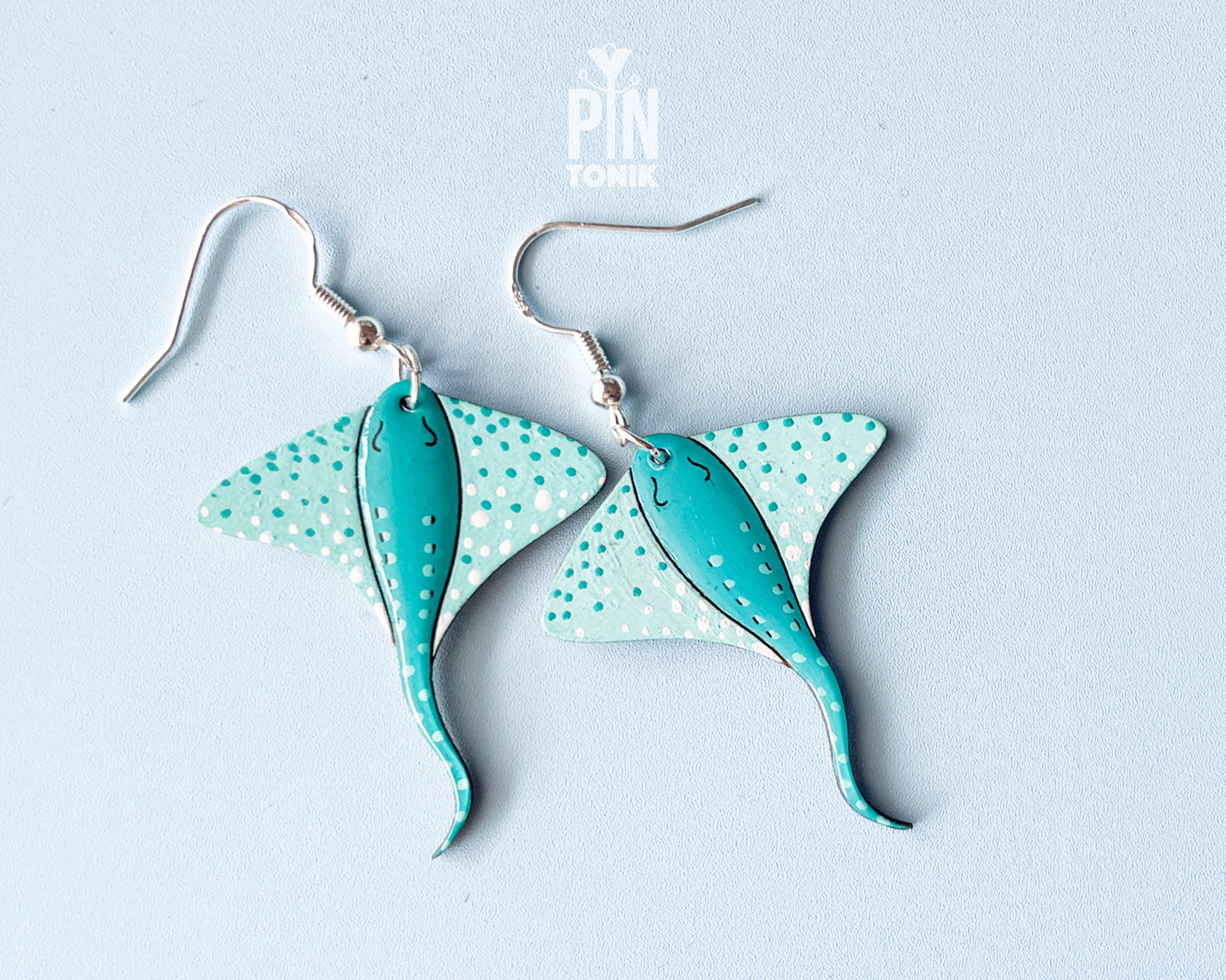 Pair of hand-painted teal wooden stingray dangle earrings with white spots and sterling silver hooks