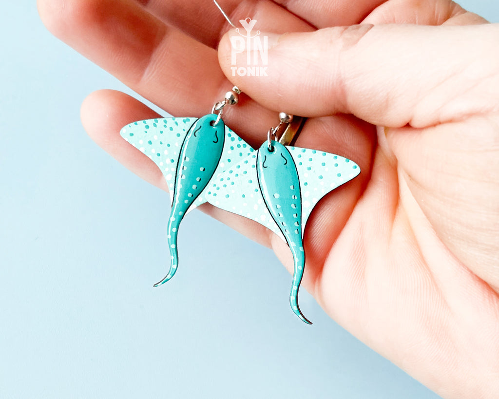 Pair of hand-painted teal wooden stingray dangle earrings with white spots and sterling silver hooks