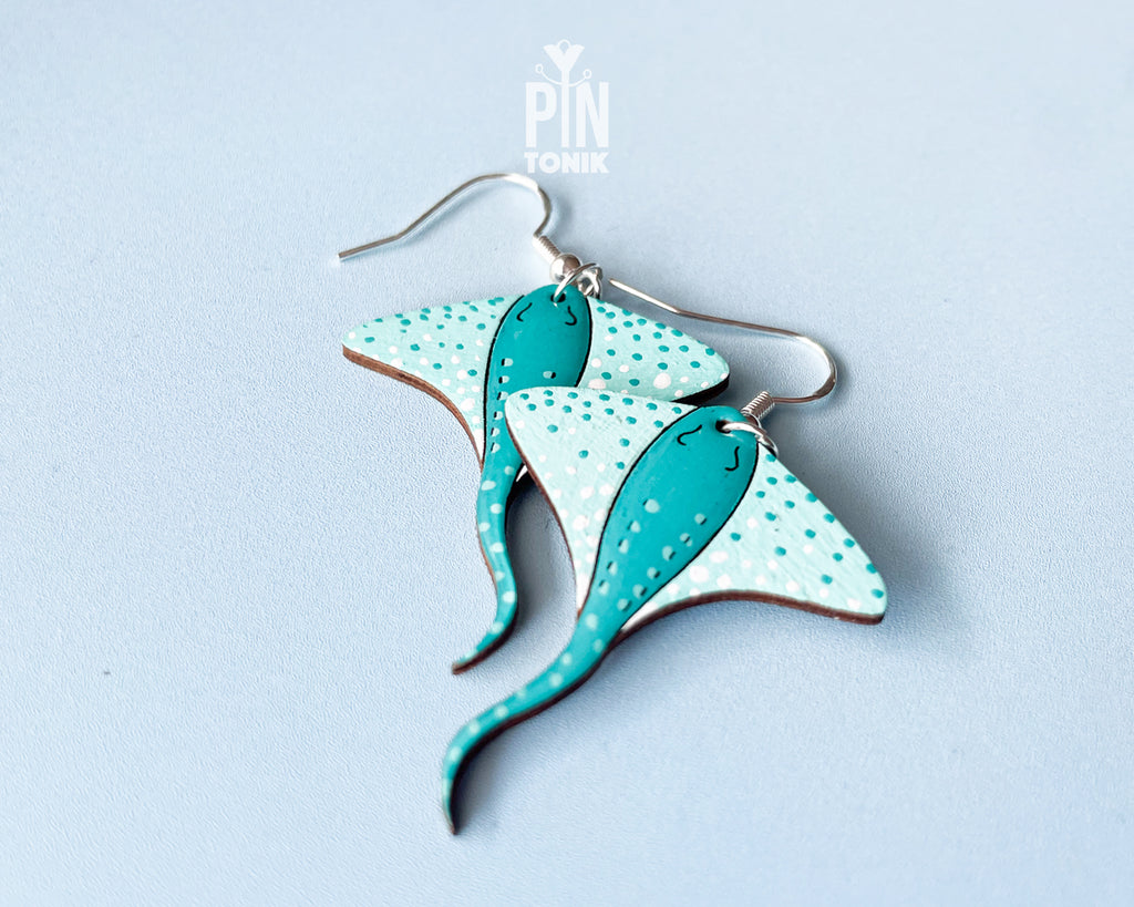 Pair of hand-painted teal wooden stingray dangle earrings with white spots and sterling silver hooks