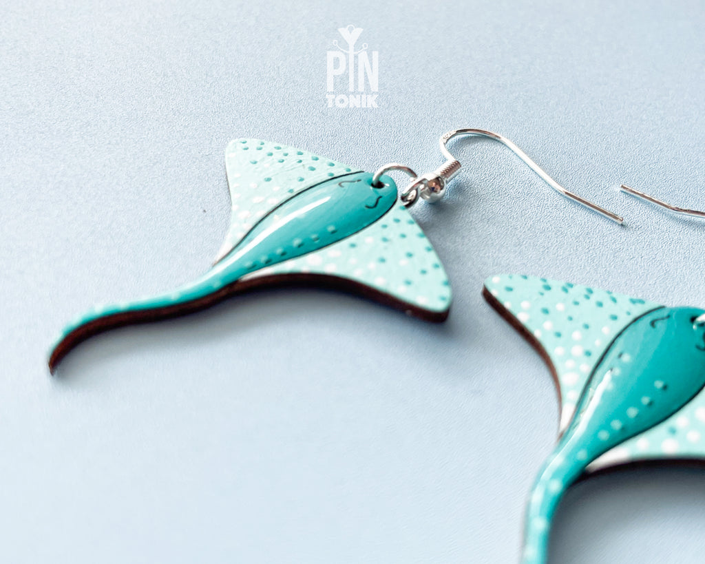 Pair of hand-painted teal wooden stingray dangle earrings with white spots and sterling silver hooks