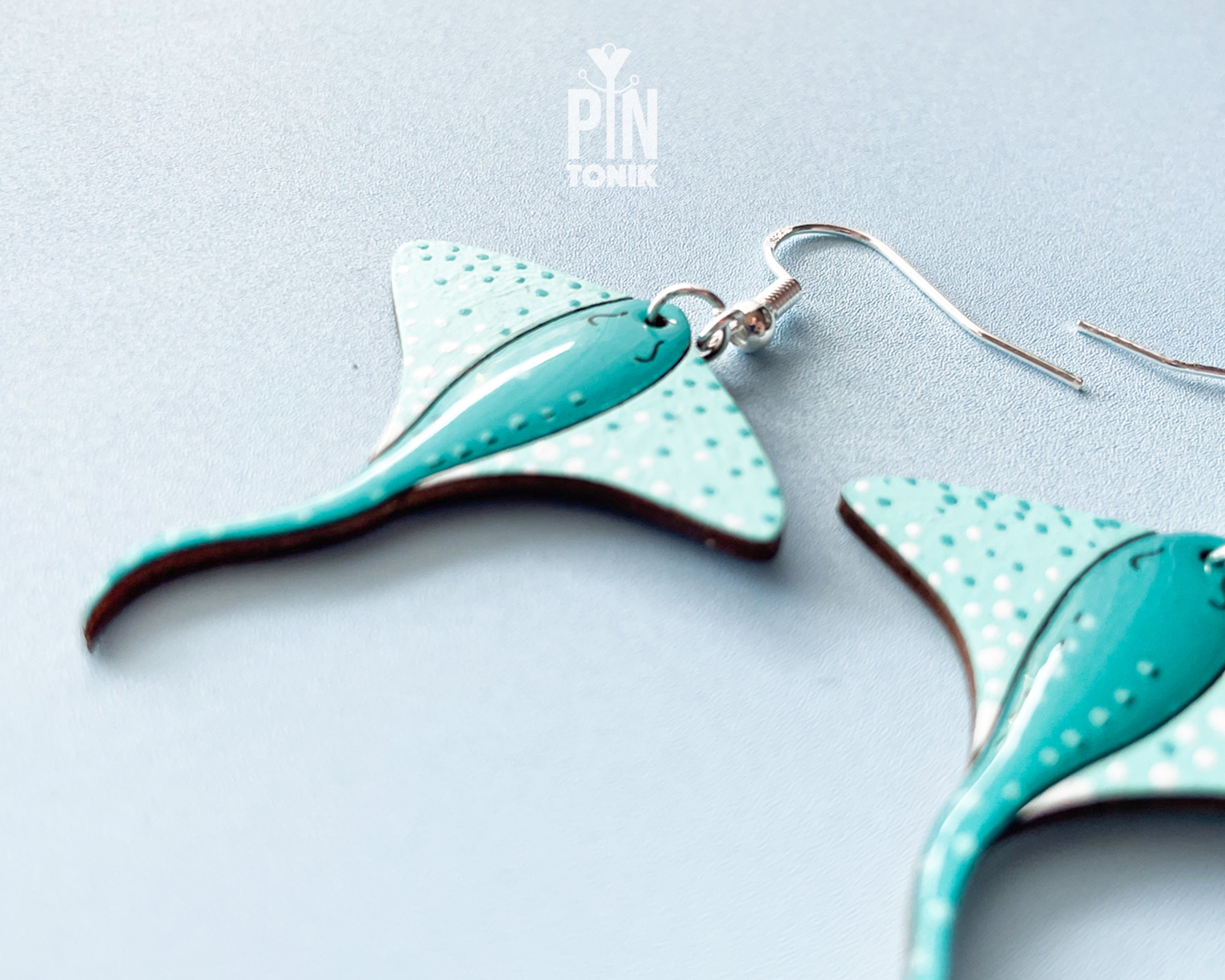 Pair of hand-painted teal wooden stingray dangle earrings with white spots and sterling silver hooks