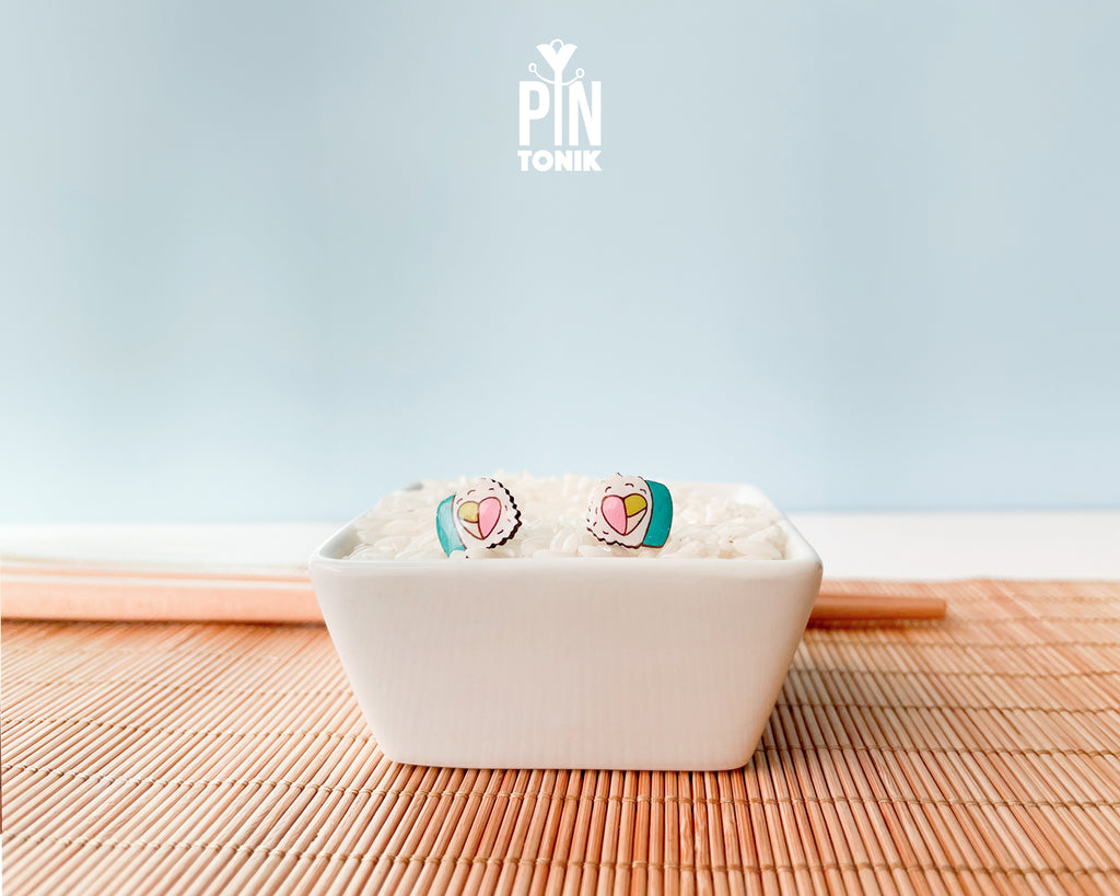 Handmade wooden sushi roll stud earrings showing a colorful pink and green filling wrapped in seaweed by PinTonik.