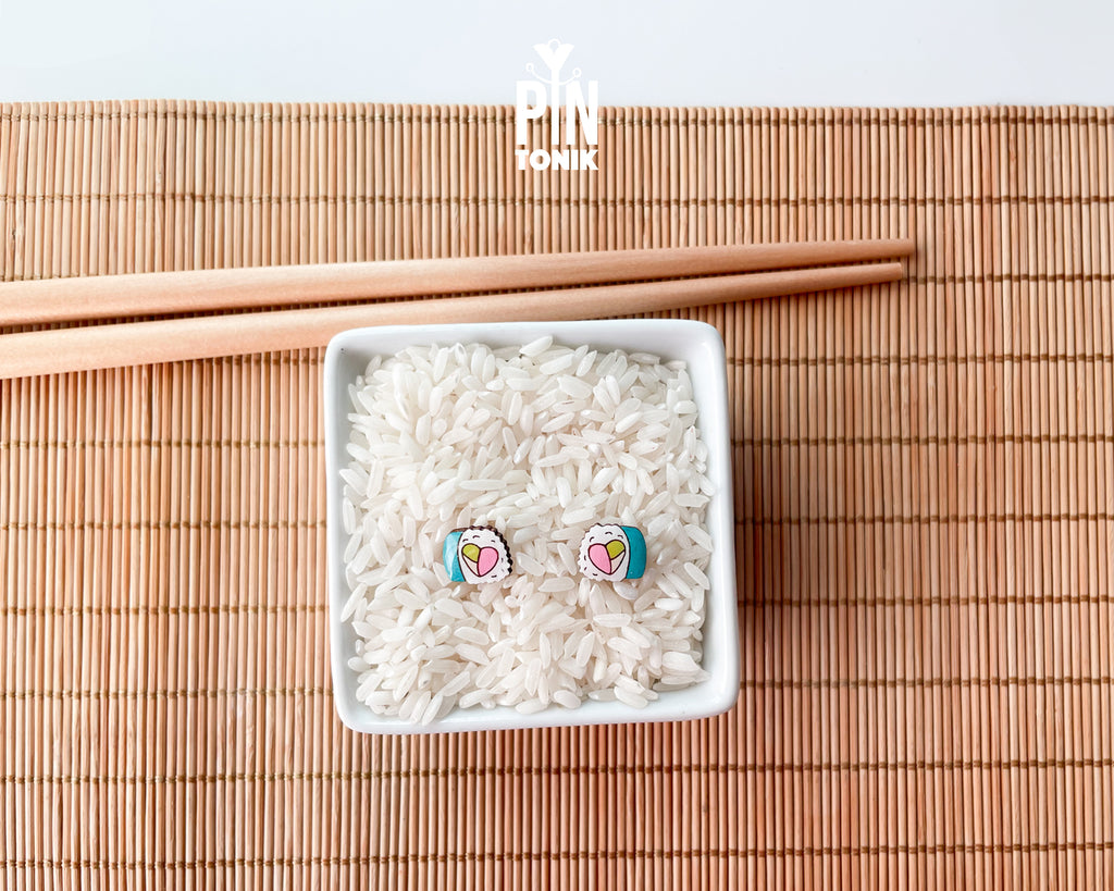 Handmade wooden sushi roll stud earrings showing a colorful pink and green filling wrapped in seaweed by PinTonik.