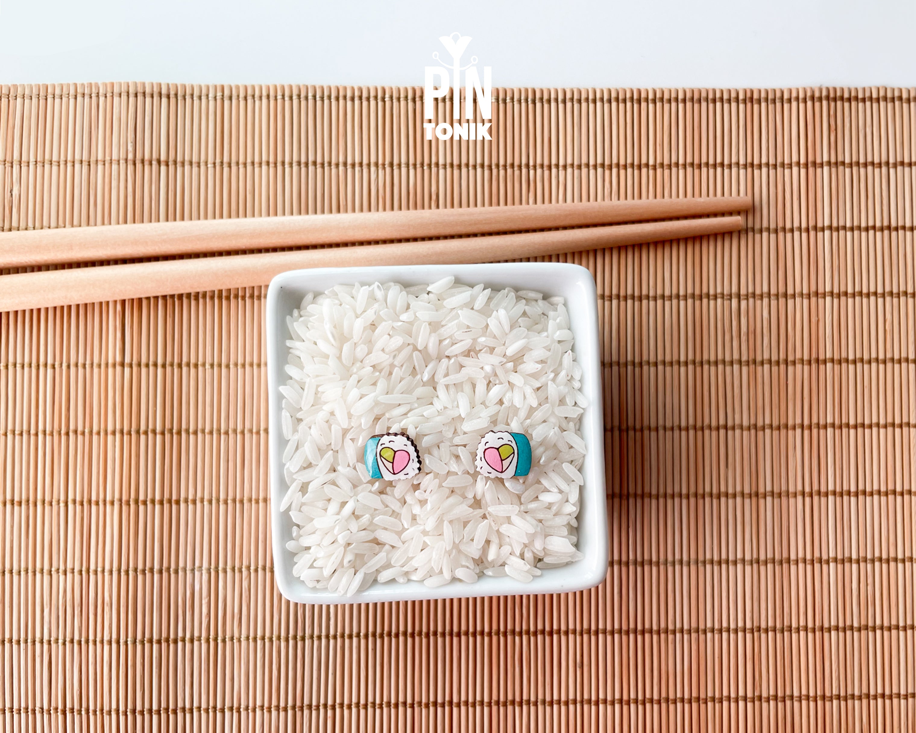 Handmade wooden sushi roll stud earrings showing a colorful pink and green filling wrapped in seaweed by PinTonik.