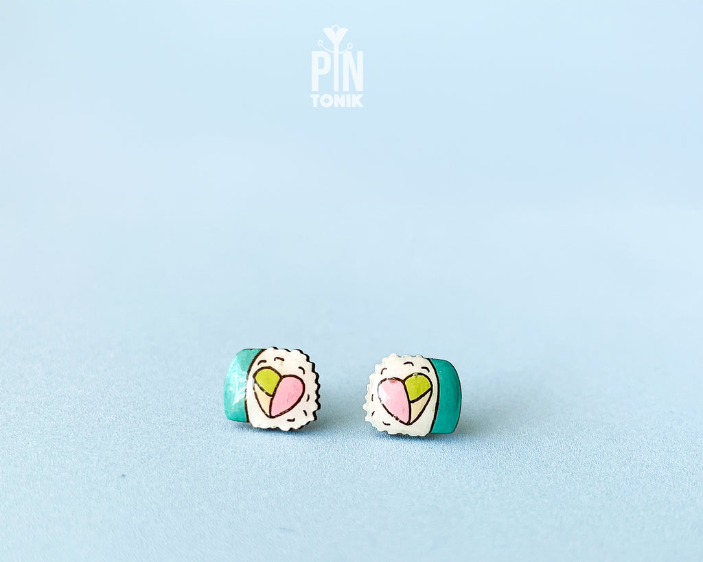 Handmade wooden sushi roll stud earrings showing a colorful pink and green filling wrapped in seaweed by PinTonik.