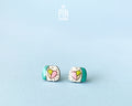 Handmade wooden sushi roll stud earrings showing a colorful pink and green filling wrapped in seaweed by PinTonik.