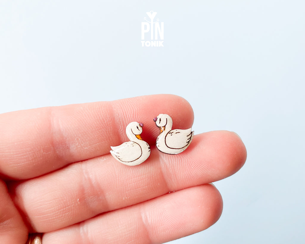 Handmade wooden white swan stud earrings with elegant black and gold detailing by PinTonik, graceful bird themed jewelry.