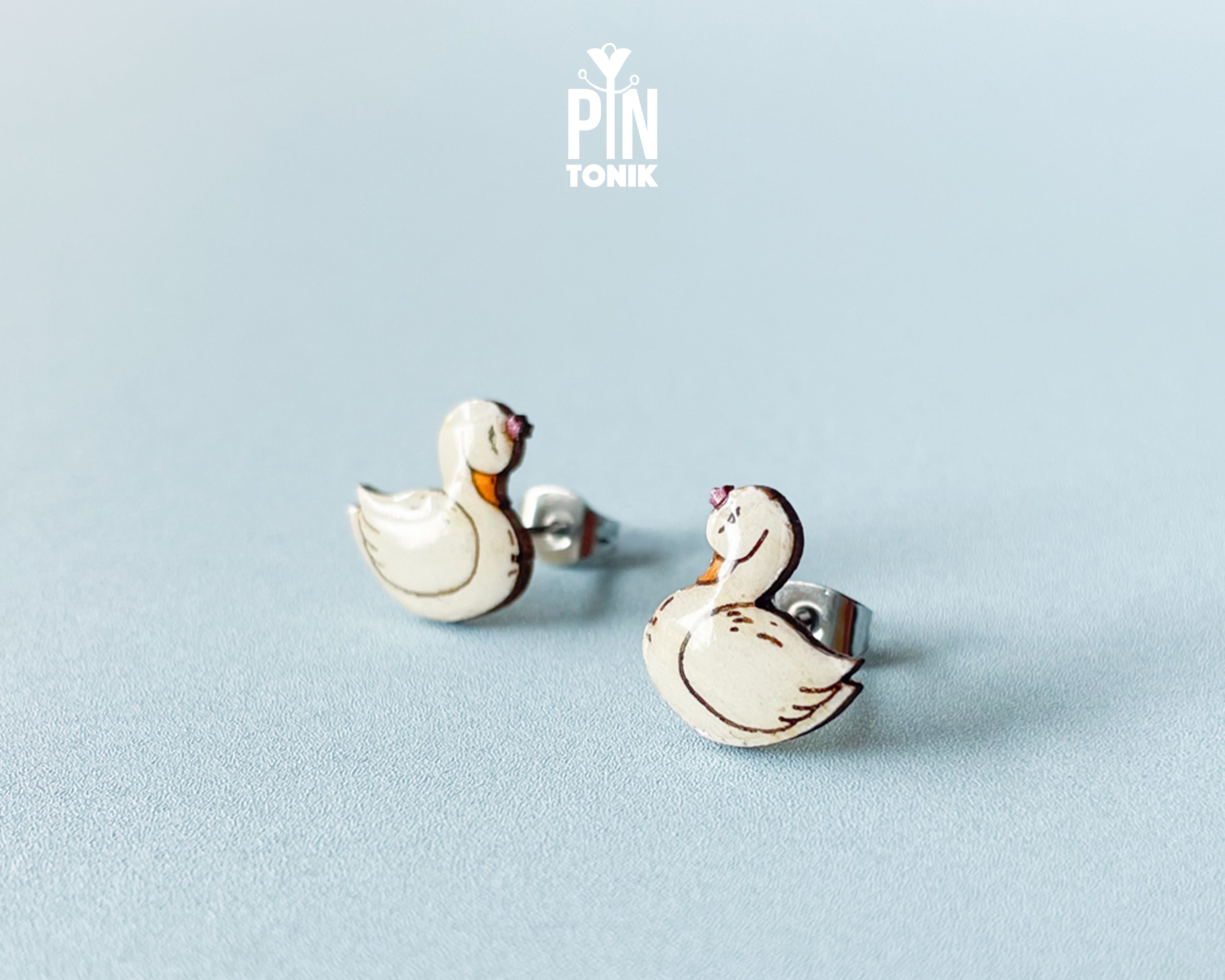 Handmade wooden white swan stud earrings with elegant black and gold detailing by PinTonik, graceful bird themed jewelry.