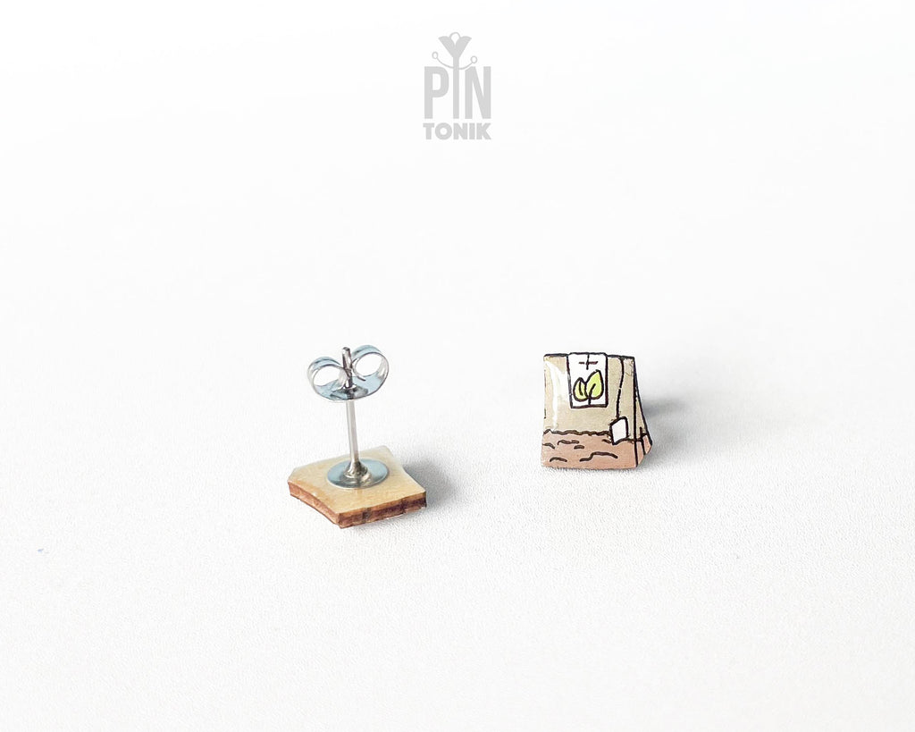 Handmade wooden tea bag stud earrings with a detailed paper bag texture, string, and tag illustration by PinTonik.