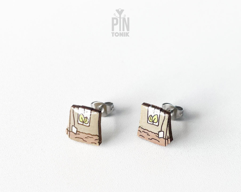 Handmade wooden tea bag stud earrings with a detailed paper bag texture, string, and tag illustration by PinTonik.
