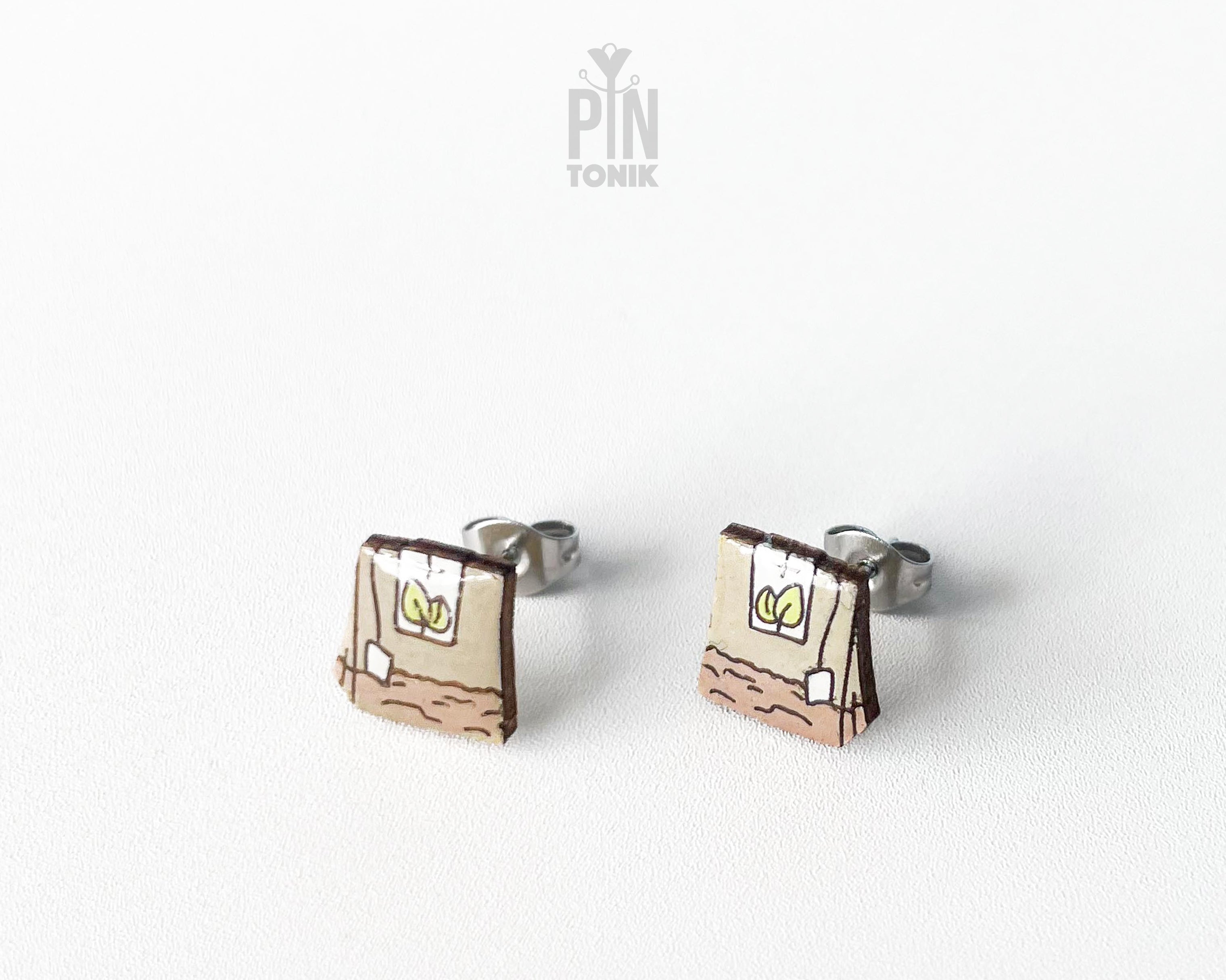 Handmade wooden tea bag stud earrings with a detailed paper bag texture, string, and tag illustration by PinTonik.