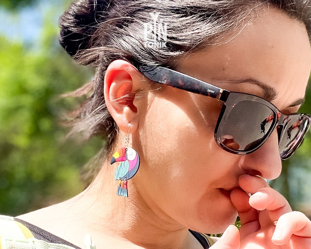 Large hand-painted wooden toucan dangle earrings with vibrant pink, yellow, and blue details on sterling silver hooks