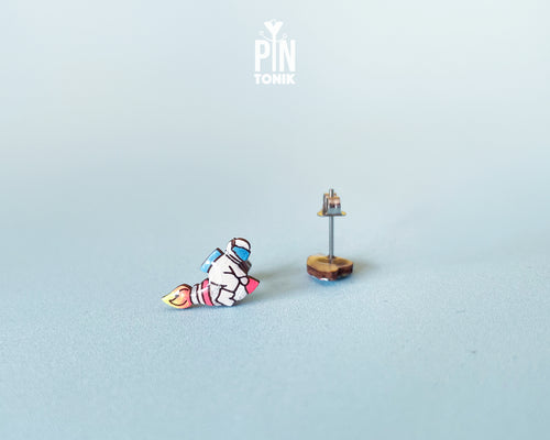 Handmade wooden mismatched stud earrings featuring an astronaut floating in space on one ear and a pastel alien UFO spaceship on the other by PinTonik.