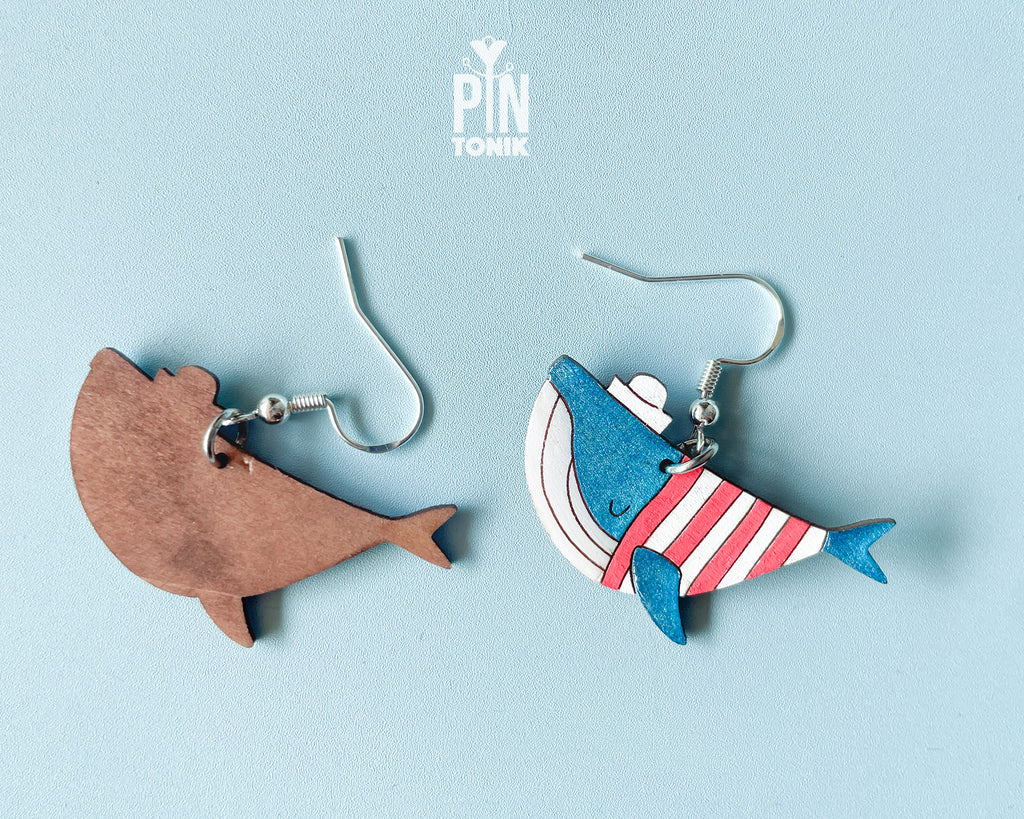 Hand-painted wooden blue whale dangle earrings wearing red and white striped sweaters and tiny sailor hats on sterling silver hooks