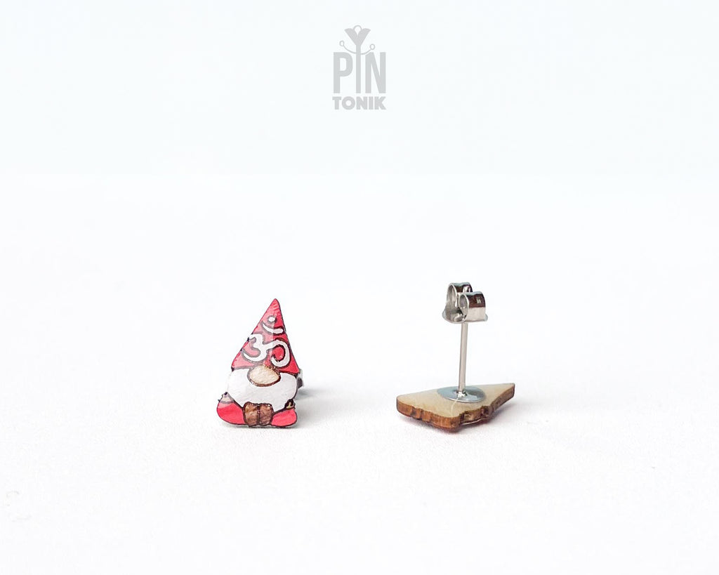 A pair of small gnome earrings. The earrings feature red hats with white Om symbol and brown shoes.