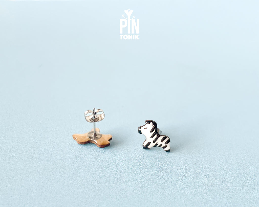 Pair of hand-painted wooden zebra stud earrings with black and white stripes and peaceful closed eyes