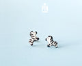 Pair of hand-painted wooden zebra stud earrings with black and white stripes and peaceful closed eyes